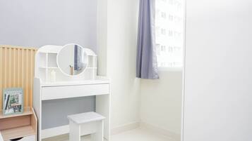 A white vanity with a mirror, a small stool, and a magazine on a shelf.