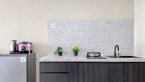 A kitchenette with a granite countertop, a sink, a stove, and a refrigerator. - Neat Studio For 2 Pax At Royal Sentul Park Apartment (Bogor)