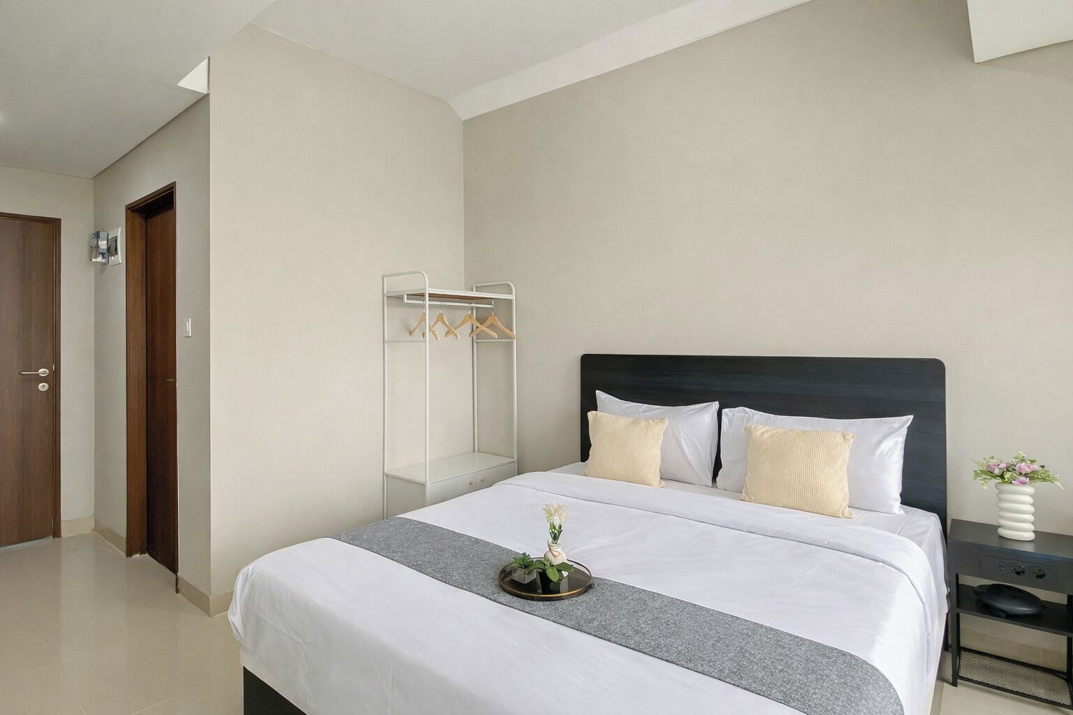 A hotel room with a bed, a bedside table, a nightstand, a wardrobe, and a mirror.