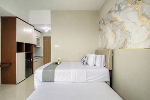 A hotel room with a bed, a small kitchenette, and a marble wall. - Functional Studio At Royal Sentul Park Apartment (Bogor)