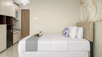 Habitación de hotel con cama, una pequeña cocina y una pared de mármol.