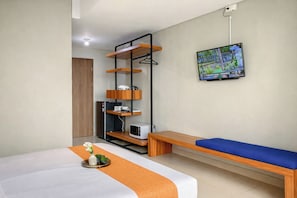 Une chambre d’hôtel équipée d’un lit, d’une banquette, d’une télévision, d’une étagère et d’un petit réfrigérateur.