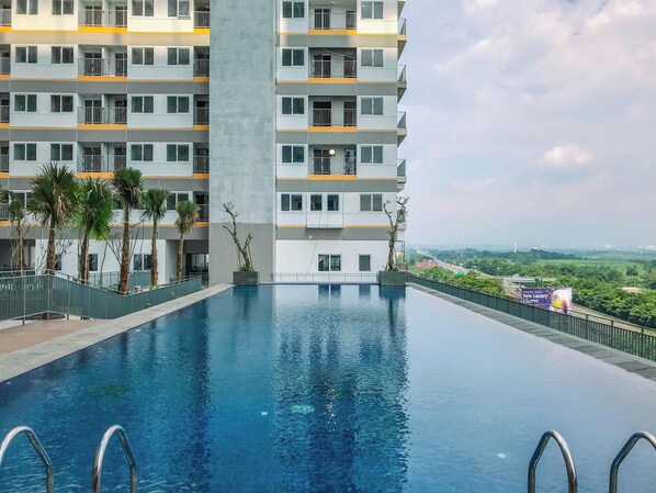 Un bâtiment moderne doté d’une piscine, de nombreux balcons et offrant une vue sur le paysage environnant.