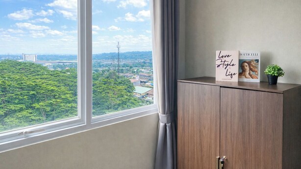 A room with a large window, a wooden cabinet, and two books titled 'Love Style Life' and 'Botticelli'. - Peaceful Studio No Kitchen At Apartment Lrt City Sentul - Royal Sentul Park (Bogor)