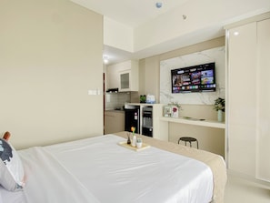 Ein modernes Hotelzimmer mit Bett, Schreibtisch, Fernseher und einer Küchenzeile.