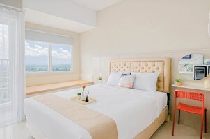 Habitación de hotel con una cama grande, un escritorio con silla, una ventana con vistas y una mesita con bandeja.