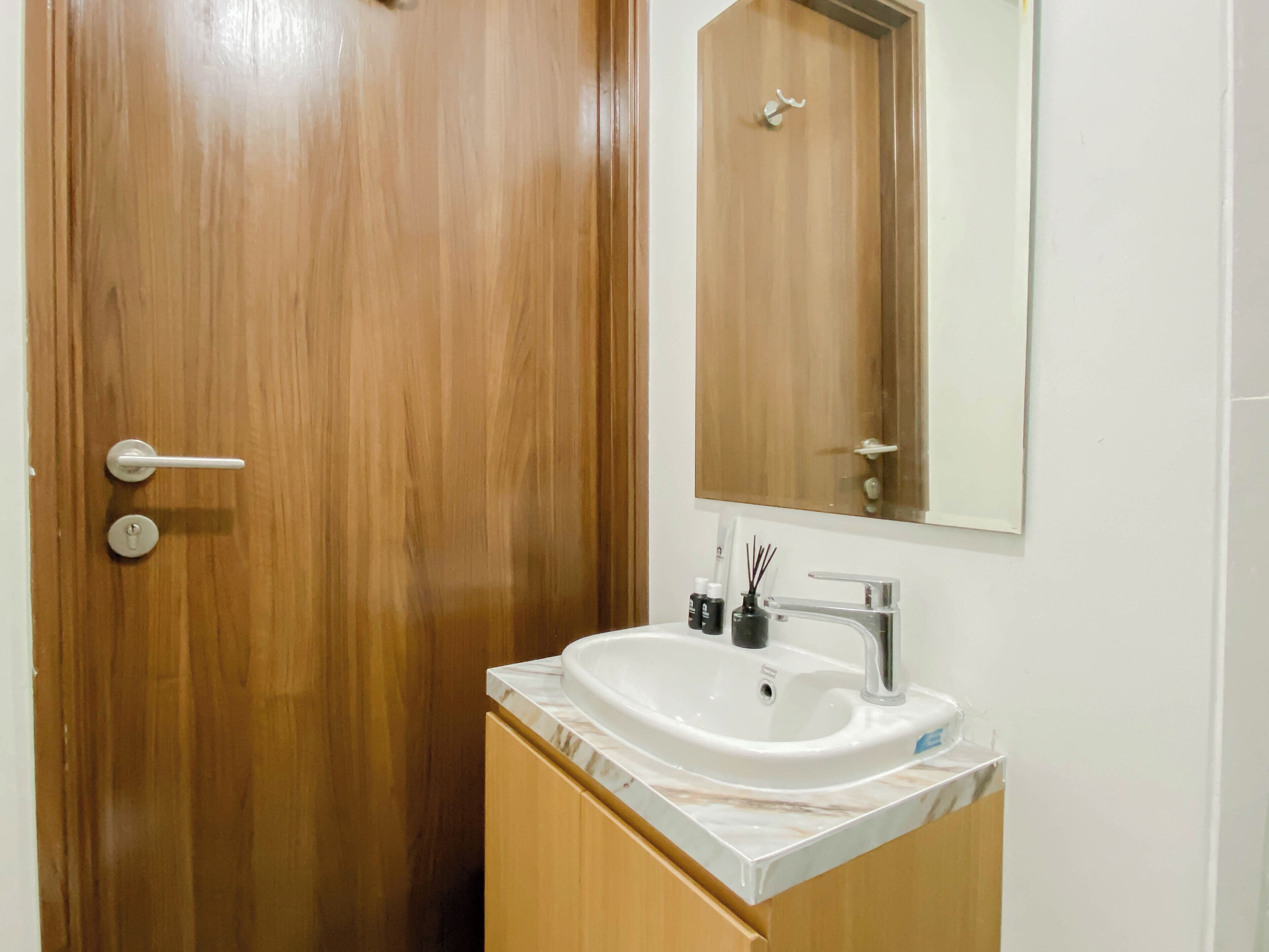 A bathroom with a wooden door, a white sink, a mirror, and a cabinet.