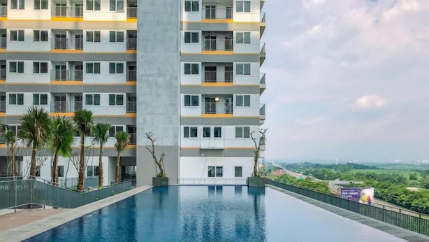 A modern multi-story building with a swimming pool in front. - Tranquil Studio For 2 Pax At Royal Sentul Park Apartment (Bogor)