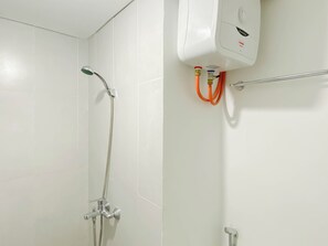 Un baño con ducha, secador de manos y barra para toallas.