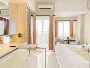 Una habitación de hotel con cama, televisión, escritorio y silla.