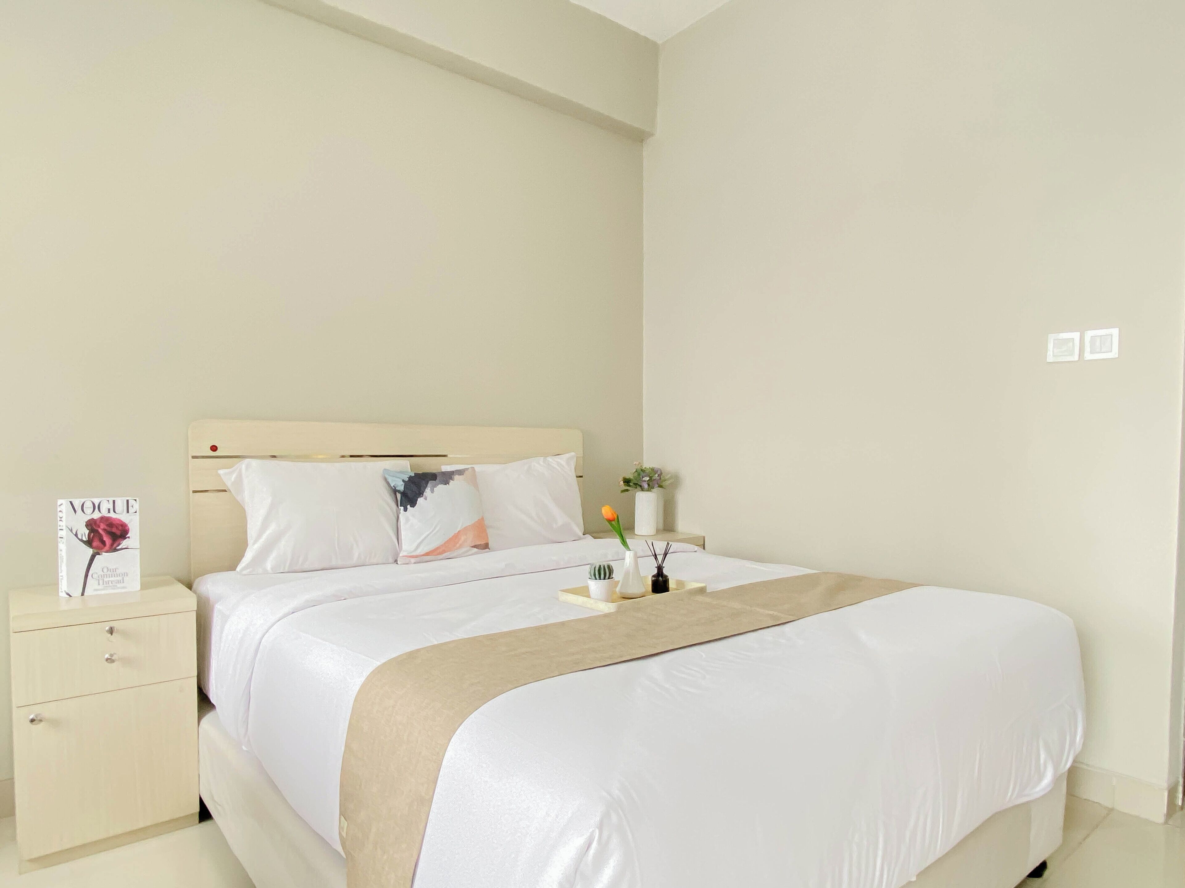 Un dormitorio ordenado con cama, mesita de noche y velador.