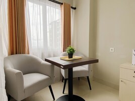 A room with a sofa, a small table with a plant, a chair, and a cabinet.