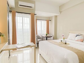 A hotel room with a bed, a desk, a chair, and a small table with a plant. - Tranquil Studio For 2 Pax At Royal Sentul Park Apartment (Bogor)