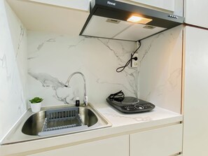 Una cocina con un lavamanos de acero inoxidable, una campana extractora empotrada y una pequeña planta en maceta.