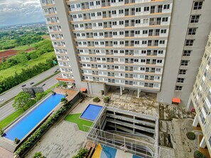 Un edificio alto con numerosi balconi, una piscina sul tetto e vista su un paesaggio verde.