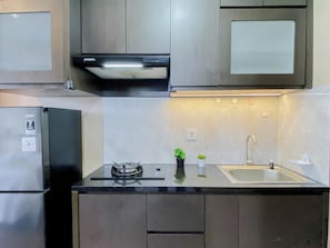 A modern kitchen with a built-in stove, a sink, and wooden cabinets. - Wooden Touch Studio Room At Apartment Lrt City Sentul - Royal Sentul Park (Bogor)