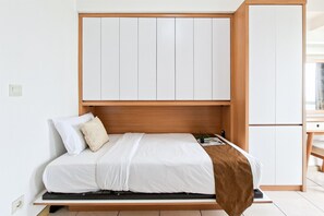 Ein Bett mit Holz-Kopfteil, weißer Bettwäsche und einer braunen Decke.