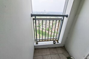 Ein Balkon mit Metallgeländer, einem Fenster und Blick auf eine Stadtlandschaft.