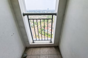 Ein Balkon mit Metallgeländer, Blick auf eine Stadtlandschaft und ein gefliestes Veranda.