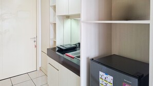 Uma cozinha com geladeira preta, micro-ondas e chaleira sobre a bancada.