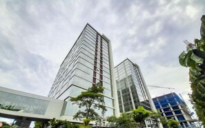Zwei Hochhäuser mit moderner Architektur, eines mit Glasfassade und das andere mit Metallverkleidung.