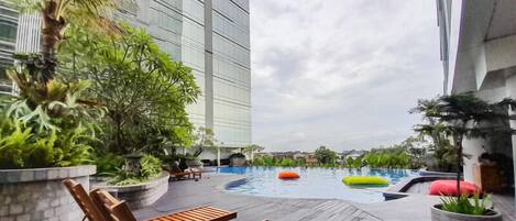 A rooftop pool area with lounge chairs, a swimming pool, and potted plants.
