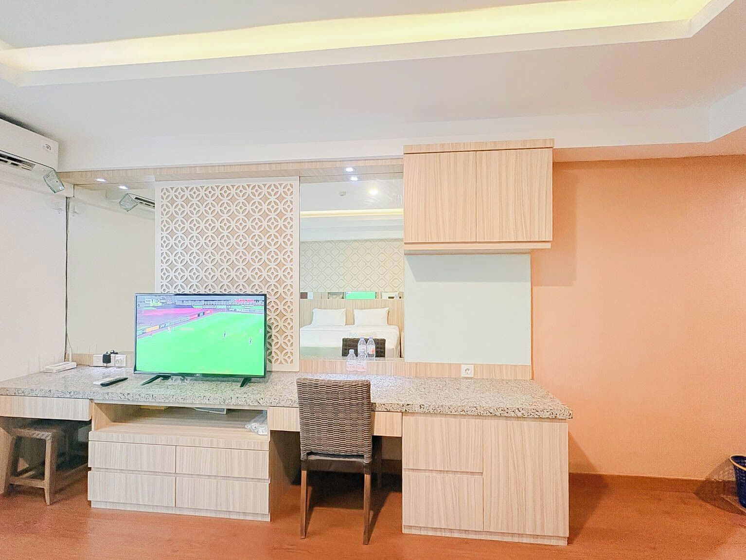 A bedroom with a bed, a desk with a computer, and a chair.