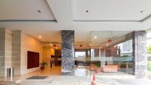 En modern hotellobby med marmorkolumner, en receptionsdisk och en glasvägg.