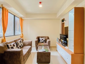 Ein Wohnzimmer mit zwei Sofas, einem Couchtisch, einem Fernseher und einem Schrank.