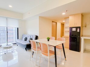 A modern apartment with a dining area, sofa, and kitchen. - 5 Pax Convenient And Homey 3Br At Meikarta Apartment (Cikarang)