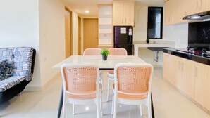A modern kitchen with light wood cabinets, a black refrigerator, and a stainless steel stove. - 5 Pax Convenient And Homey 3Br At Meikarta Apartment (Cikarang)