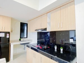 A modern kitchen with light wood cabinets, a black marble countertop, and a built-in stove.