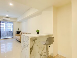 Uma sala de estar moderna com uma ilha de mármore, um sofá, uma poltrona e uma planta em vaso.