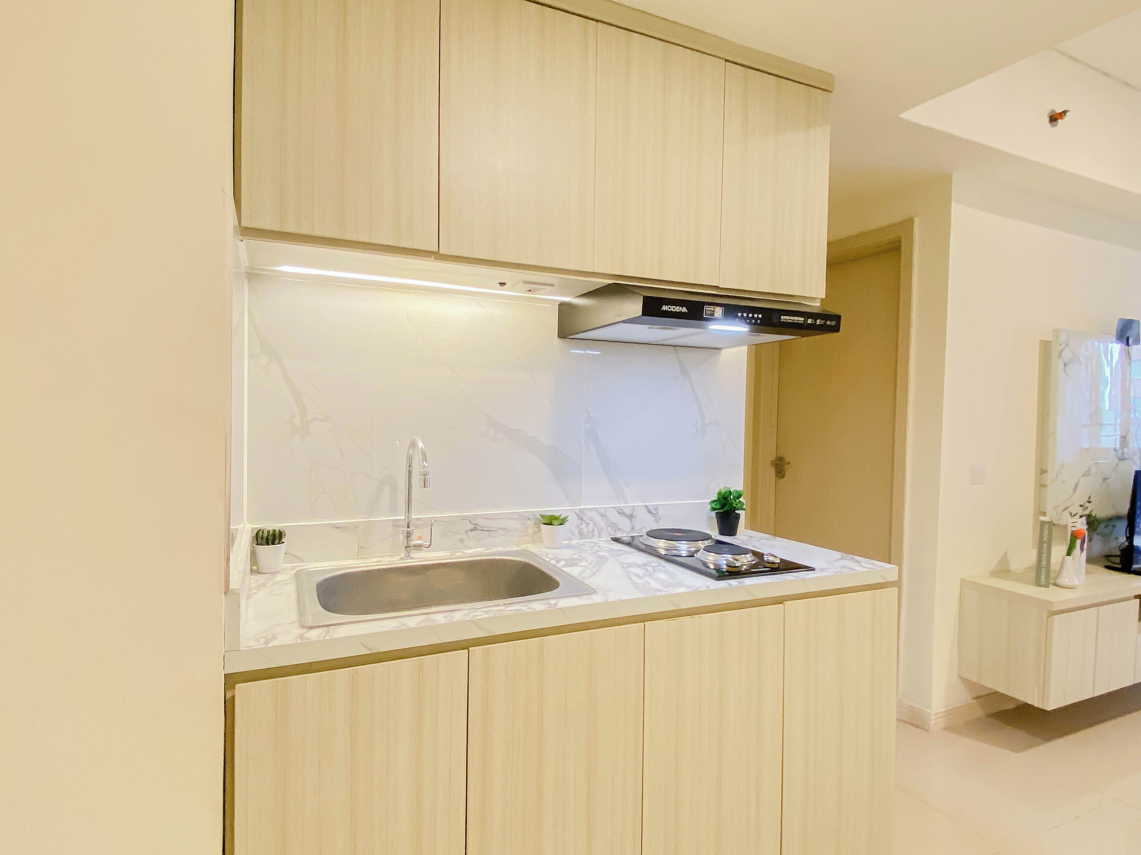 Una cocina moderna con estufa integrada, pileta y campana extractora de acero inoxidable.