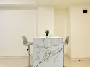 Un tavolo con piano in marmo, due sedie, una piccola pianta in vaso e una parete bianca.