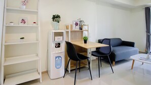 A modern living room with a dining area, a water dispenser, and a sofa. - Restful And Spacious 3Br At Apartment Meikarta District 1 (Cikarang)