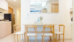 Una cucina moderna con frigorifero, piano cottura e pensili in legno. C'è un'area pranzo con tavolo e quattro sedie.