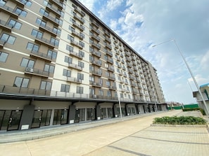 A multi-story residential building with balconies, a covered walkway, and a paved entrance area. - Neat Studio For 2 Pax At Meikarta District 2 Apartment (Cikarang)