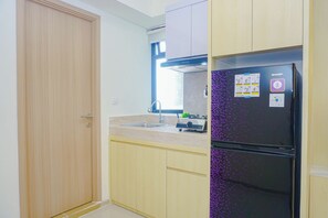 Una cocina con refrigerador, pileta y armarios de madera.