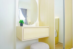 Ein Badezimmer mit Spiegel, einer kleinen Topfpflanze, einem hellen Waschtisch und einer Toilette.