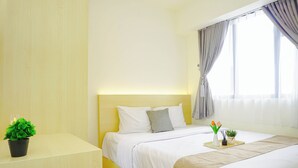 A hotel room with a bed, bedside table, and a window with curtains. - 2Br Near Paramadina University At Meikarta District 2 Apartment (Cikarang)