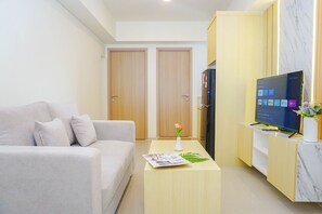 Ein modernes Wohnzimmer mit einer Couch, einem Couchtisch mit einer Zeitschrift, einem Fernseher und einem Schrank.