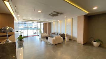 Um lobby moderno com balcão de recepção, área de estar e amplas janelas.