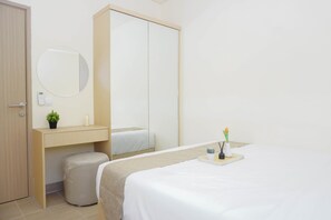 Ein Hotelzimmer mit einem Bett, einem Nachttisch, einem Spiegel, einer kleinen Topfpflanze und einer Toilette.
