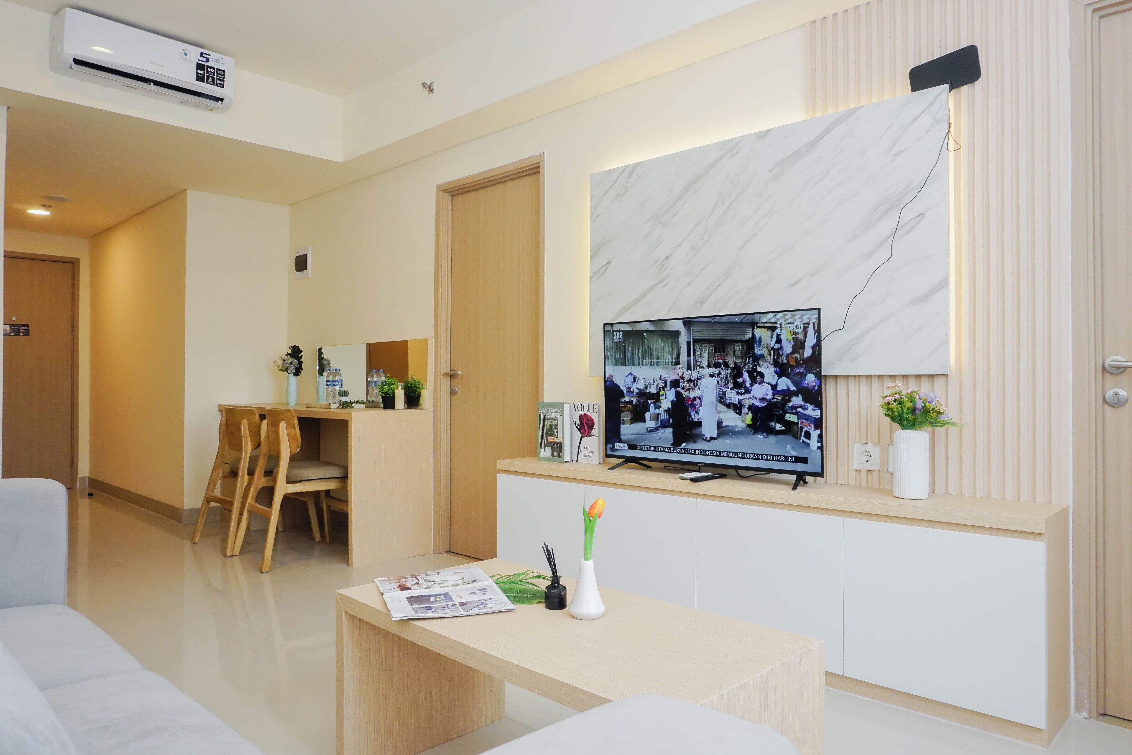 Quarto de hotel moderno com TV de tela plana na parede, escrivaninha de madeira, sofá branco e parede decorativa em mármore.