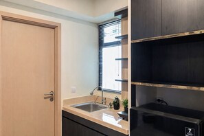 Eine Küche mit Holztür, einem Fenster mit Rollo, einer Spüle und einem schwarzen Gerät.
