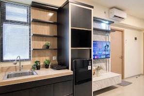 Eine moderne Küche mit Einbauherd, Spüle und einem flachbildschirmigen Fernseher an der Wand.