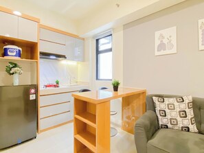 En kompakt bolig med tekøkken, spisebord, sofa og et vindue der giver naturligt lys.