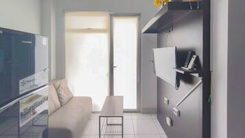 Een moderne woonkamer met een bank, salontafel, flatscreen televisie en een schuifdeur naar een balkon.
