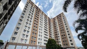 A high-rise residential building with multiple floors, large windows, and a parking area in front. - Restful And Warm Studio At Apartment Menara Rungkut (Surabaya)